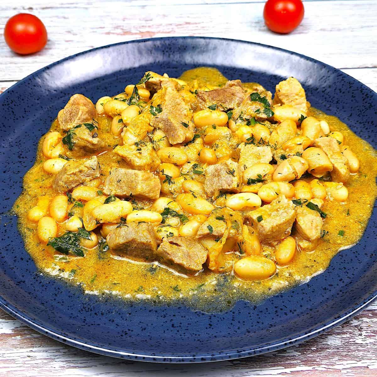 Blue Plate of Creamy Pork and White Bean Stew with fresh bread - timeaskitchen.com
