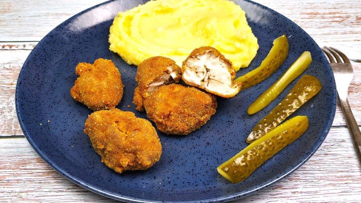 Breaded Pork Brain Served on Blue Plate With Mashed Potatoes and Sun-Pickled Cucumbers
