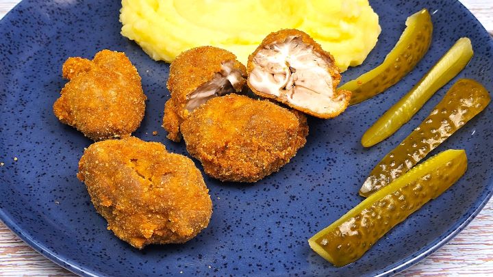 A close-up cut of a crispy breaded pork brain showing the contrast between the crunchy breadcrumb crust and the rich, creamy interior texture.