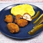 Transylvanian Crispy Breaded Pork Brain Served on Blue Plate With Mashed Potatoes and Homemade Sun-Pickled Cucumbers