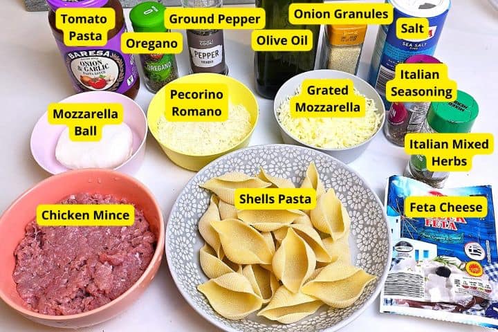 Ingredients for chicken stuffed pasta shells including jumbo shells, chicken mince, feta cheese, mozzarella, tomato sauce, and spices.