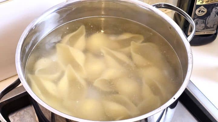 Boiling jumbo pasta shells in a large pot of salted water.