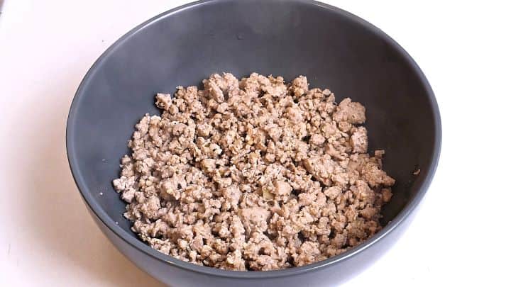 Sautéed seasoned chicken mince cooling in a ceramic bowl.