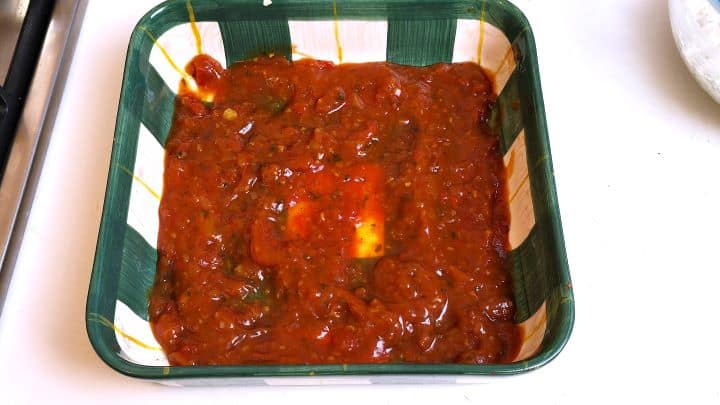 Onion-garlic tomato sauce spread over the bottom of a ceramic baking dish.