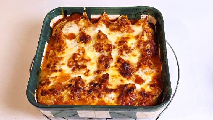 Baking dish filled with cheesy chicken stuffed shells baked in tomato sauce and topped with melted mozzarella cheese.