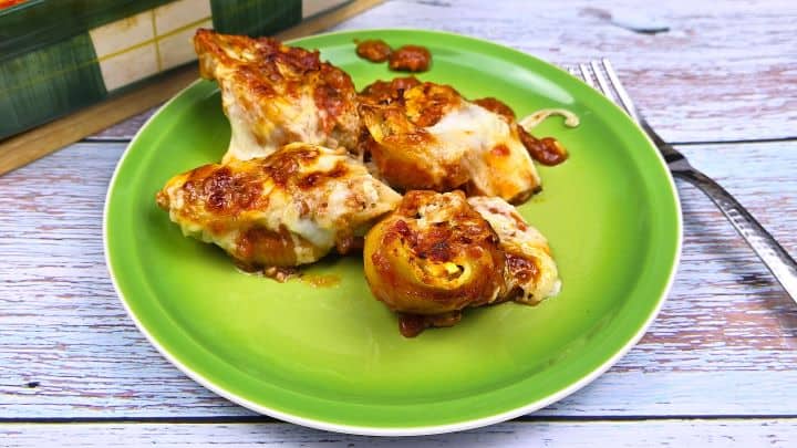 Four cheesy chicken stuffed shells served on a green plate.