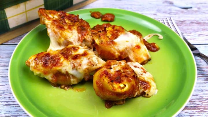 Close up of a baked cheesy chicken stuffed shell served on a green plate showing gooey melted mozzarella cheese.