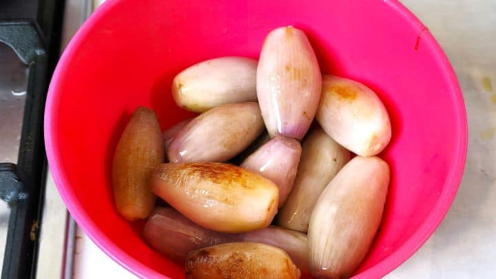 Golden browned whole shallots removed from the pot and set aside in a bowl.