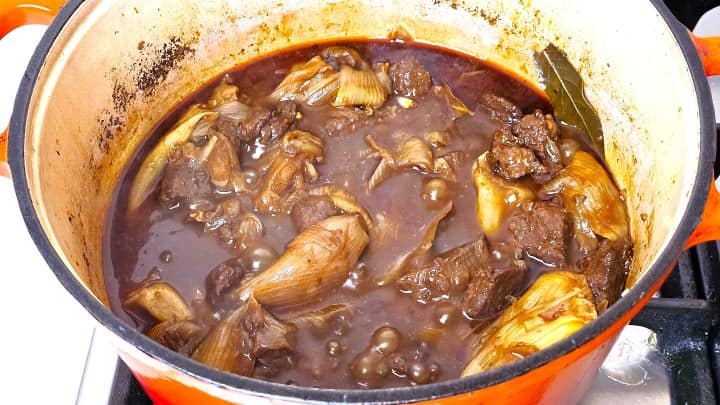 Cooked Greek beef stifado in the Dutch oven with tender beef, whole glazed shallots, and rich thick gravy.