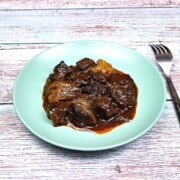 Authentic Greek beef stifado with tender beef chunks and whole caramelized shallots in a rich red wine sauce.