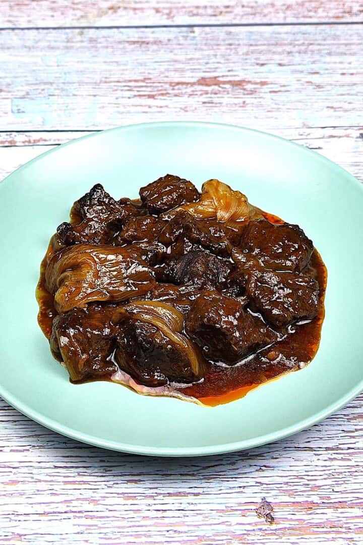 Authentic Greek beef stifado with tender beef chunks and whole caramelized shallots in a rich red wine sauce.