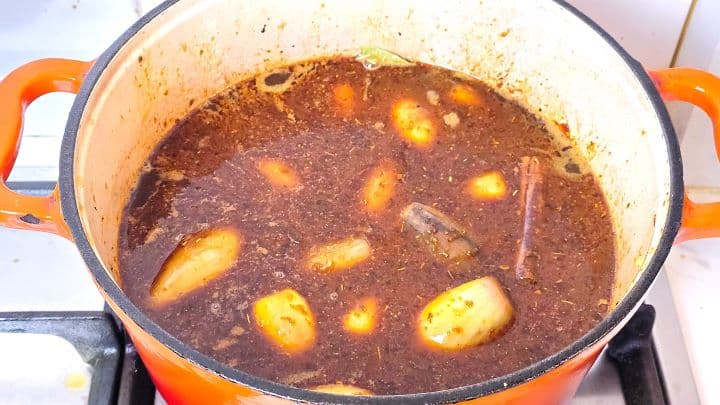 Whole browned shallots and beef simmering together in spiced red wine broth in the Dutch oven.
